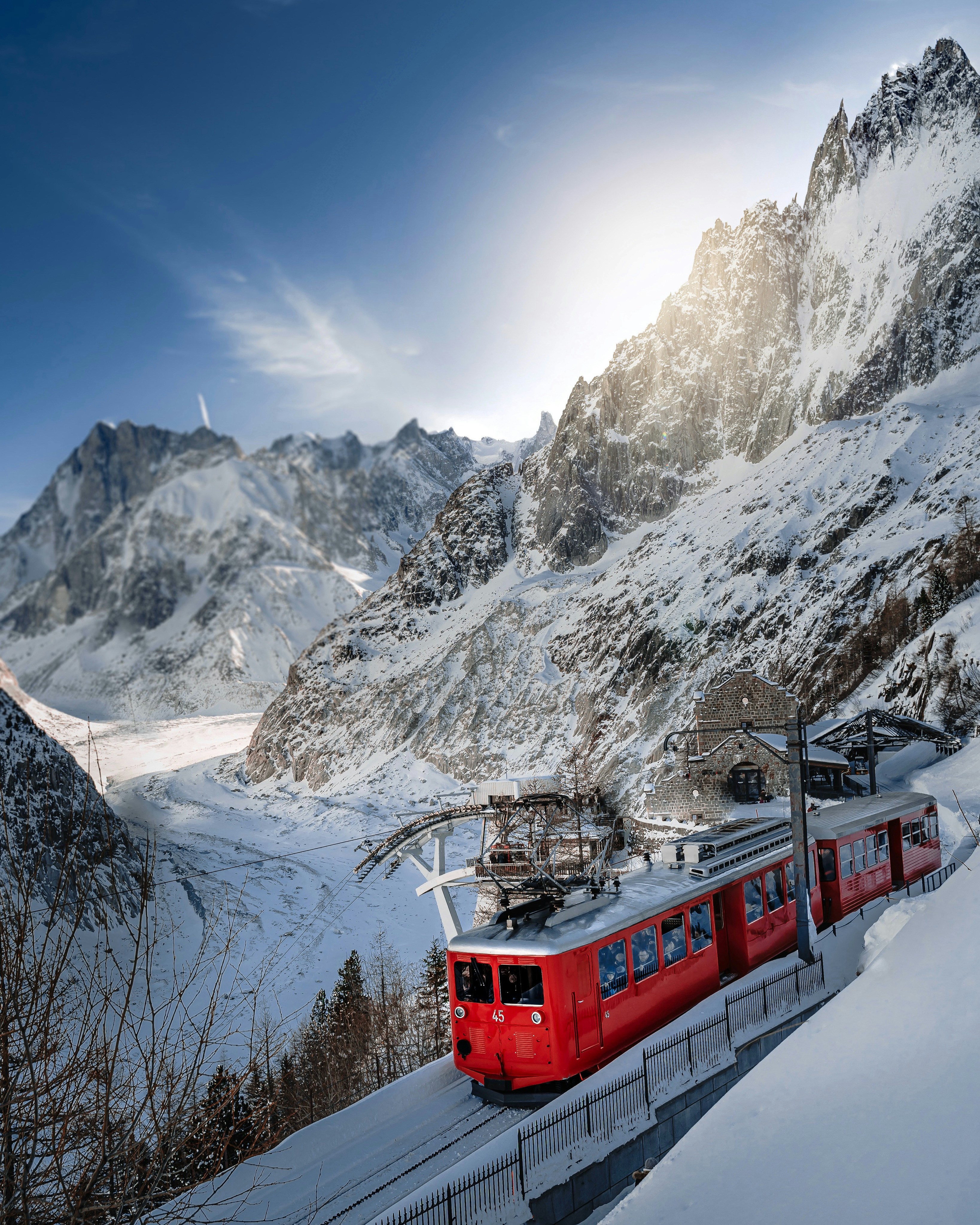 Red Chamonix train driving through a snowy valley.